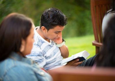 guy reading scriptures outside with friends