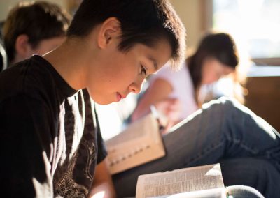 younger boy reading scriptures with family